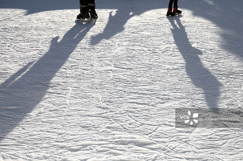 人们在粗糙的冰面上滑冰的脚和影子图片素材