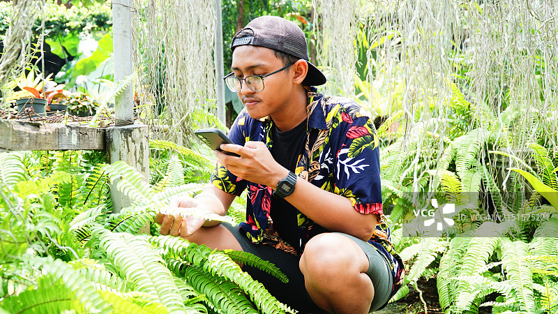 在花园里分析花卉植物状况的年轻男植物学家图片素材