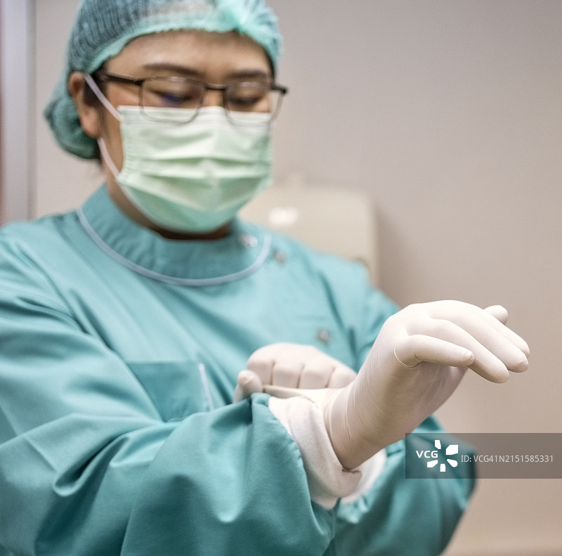 牙科手术室里，穿手术服的牙医戴外科手套图片素材