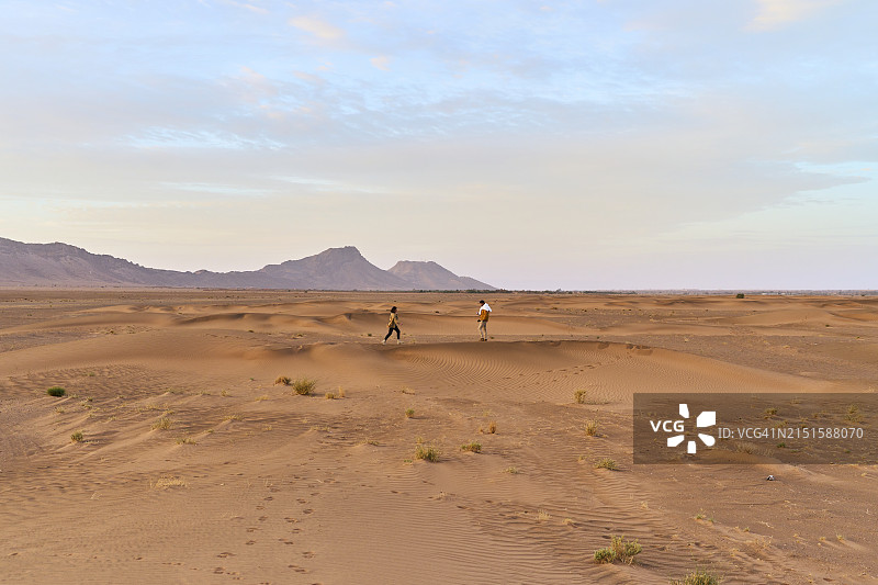 在扎戈拉沙漠中奔跑的年轻情侣的侧视图图片素材
