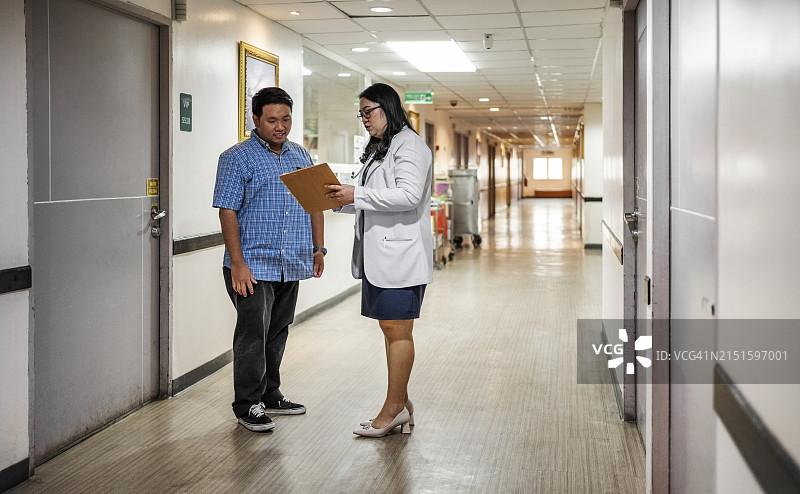 医生在医院走廊向患者丈夫展示医疗结果图片素材