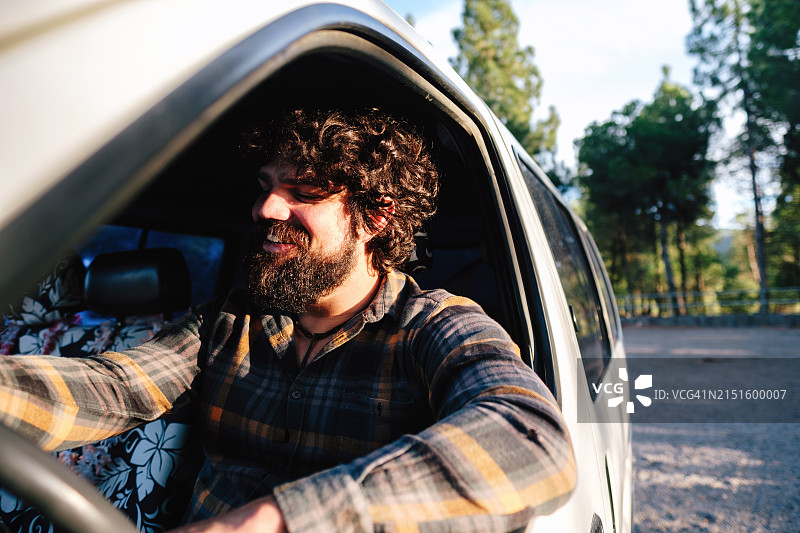 留着胡须的男人正在驾驶一辆白色厢型车图片素材