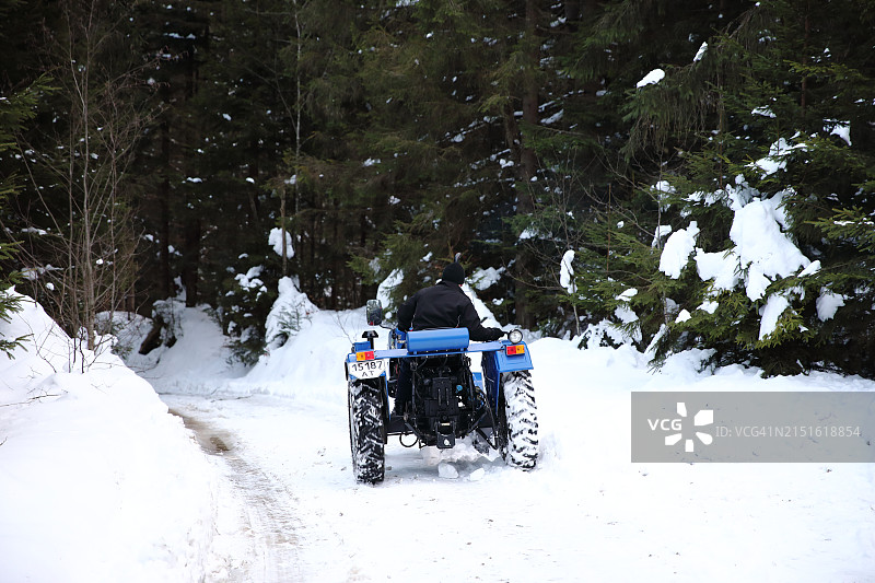 小型拖拉机在森林雪路上行驶图片素材