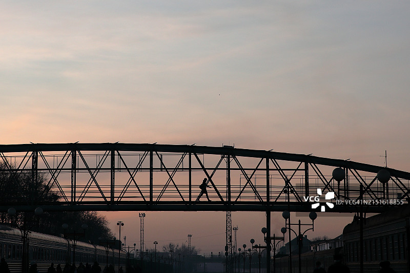 黎明时分的火车站，人行天桥上乘客的剪影图片素材