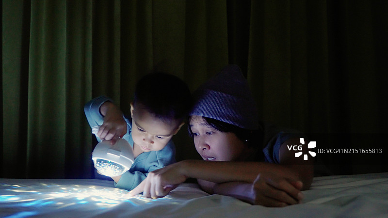 妈妈和男婴在卧室玩投影灯图片素材