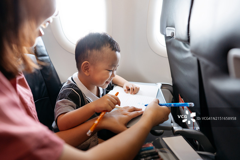 在飞机客舱里画画的亚洲小男孩图片素材