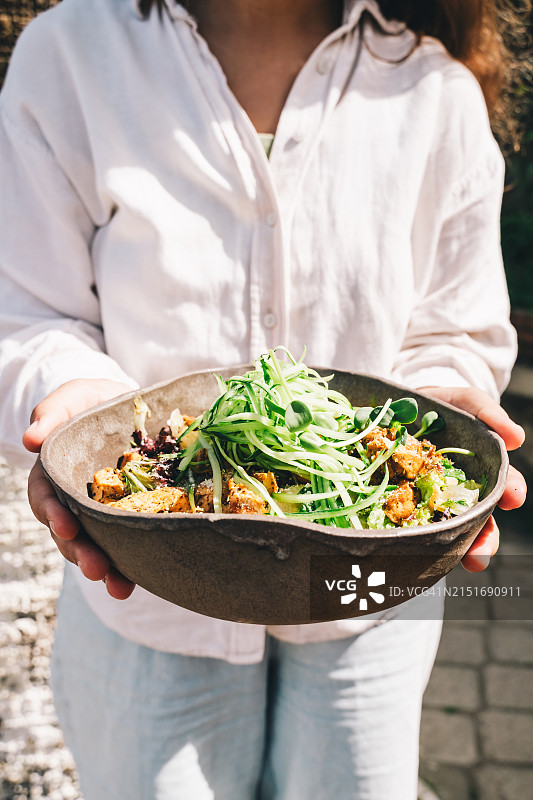 碗里装着健康食品。大盘子里装着新鲜蔬菜和肉。阳光明媚的一天，在咖啡馆里用餐。图片素材