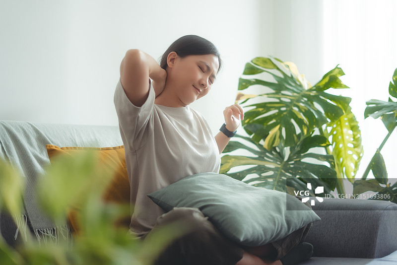 在家中客厅沙发上颈椎疼痛的亚洲女人图片素材