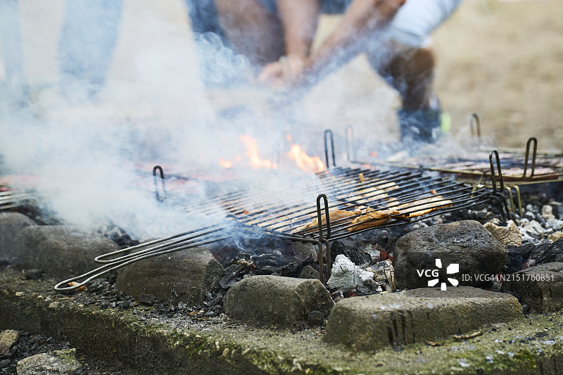 身份不明的男人在春日为家人烹饪户外烧烤图片素材