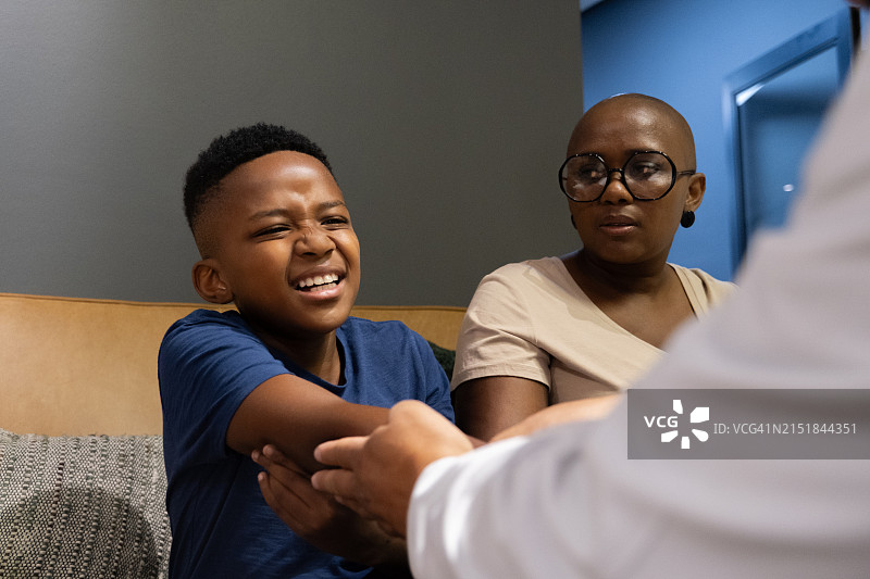 手臂疼痛，和母亲在医院的男孩图片素材