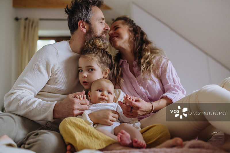 新生儿的核心家庭肖像：姐姐充满爱意地看着小妹妹图片素材