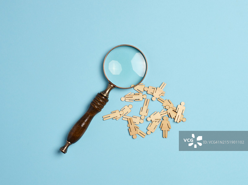 蓝色背景上的木制小人和放大镜 招聘概念，寻找人才图片素材
