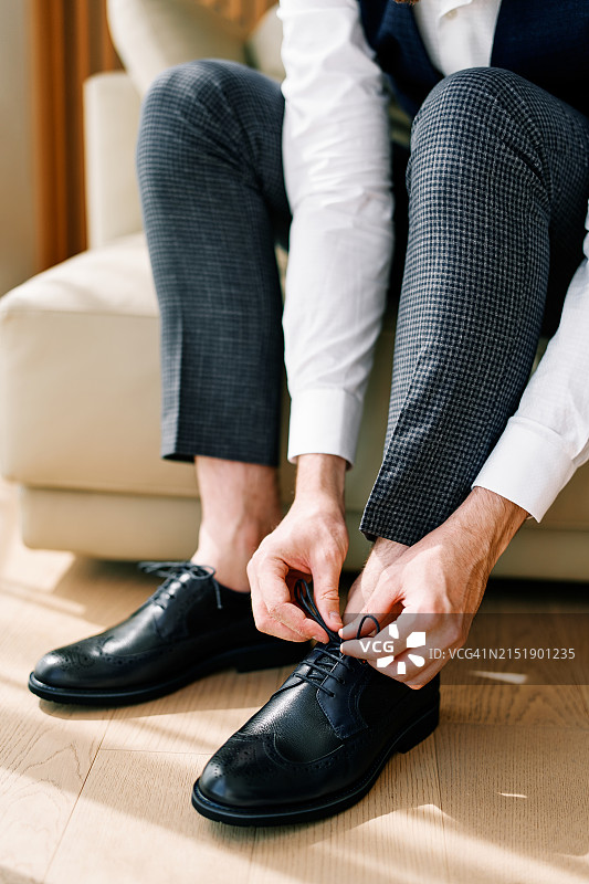新郎坐在沙发上系黑色皮鞋图片素材