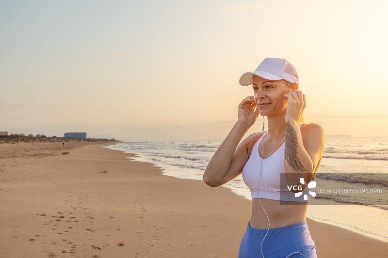 一位在海滩上跑步听音乐的年轻貌美女子的肖像图片素材