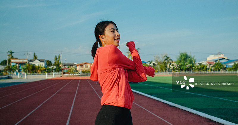 年轻的亚洲女运动员在跑步前进行热身运动图片素材