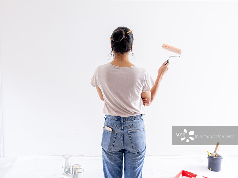女子在装修房子时粉刷墙壁的背影图片素材