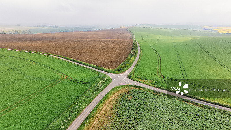 雾蒙蒙的春日清晨，英国乡村公路的道路交叉口航拍景观图片素材