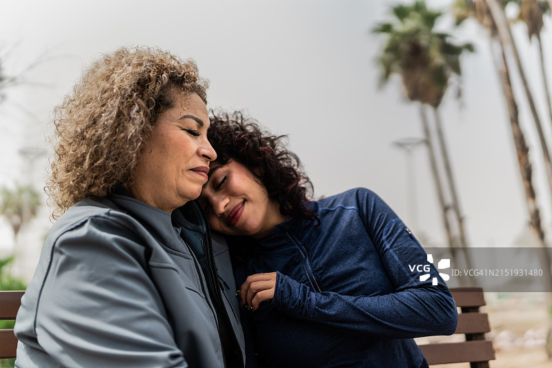 母女在公园长椅上面对面图片素材