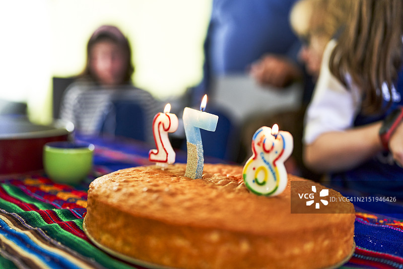 生日蛋糕上的数字蜡烛侧面图，背景有人群图片素材