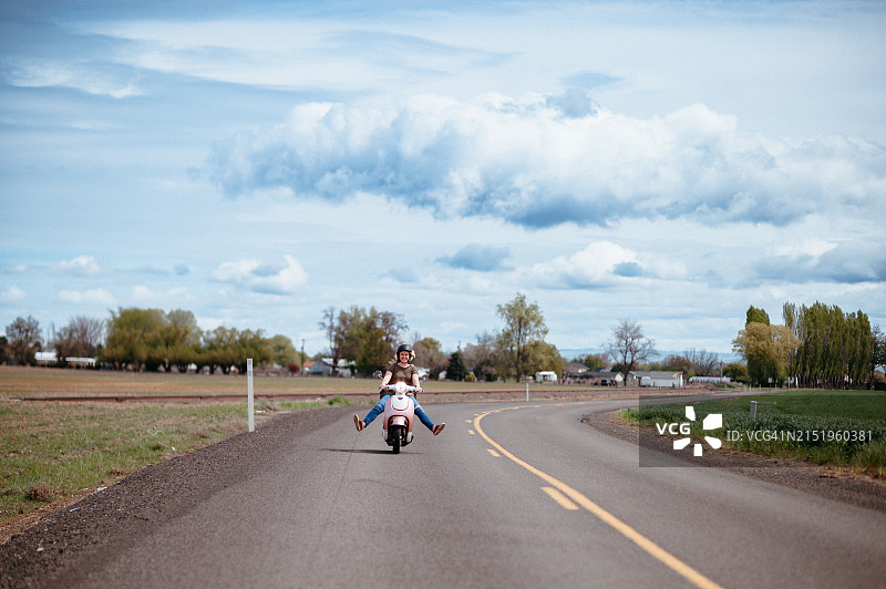 女人在乡村道路上骑摩托车图片素材