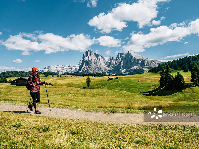 一名妇女在塞伊塞尔阿尔姆步道上拄着登山杖行走图片素材