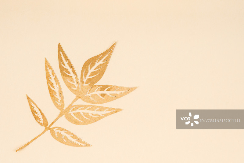 米色纸背景上的棕色折纸树叶剪纸，带有复制空间图片素材