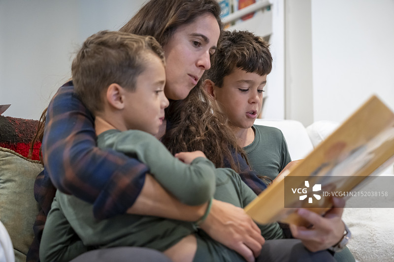 母亲在膝上给两个小兄弟读书图片素材