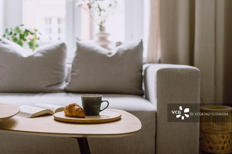 聚焦于咖啡桌上的竹制托盘，上面有杯子、烘焙食品和书图片素材