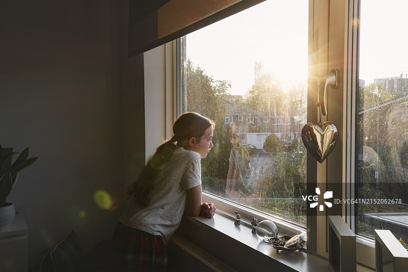 年轻女孩望着卧室窗外的强烈情感图片素材