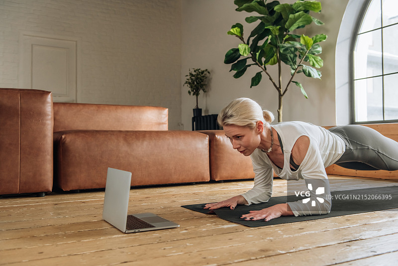 女人在笔记本电脑上看视频并在线练习瑜伽图片素材