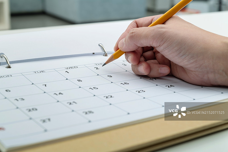 女人手持铅笔在日历页上书写图片素材