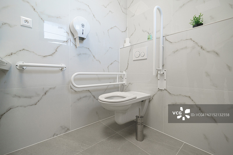 医疗建筑内白色现代洁净的马桶特写，适合残疾人士的小浴室图片素材