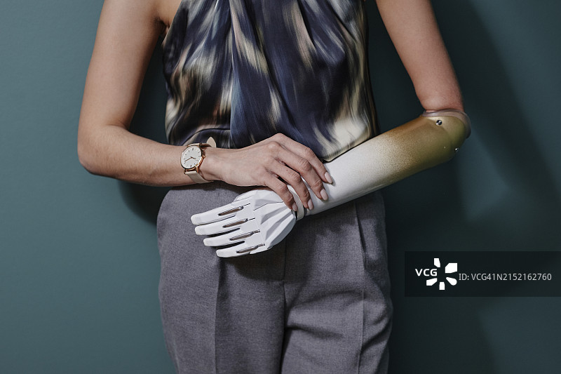 站在绿色墙壁前的仿生手臂年轻女子图片素材