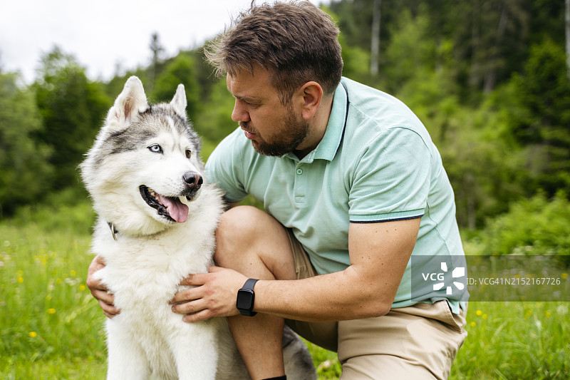 中年男人跪在哈士奇犬旁图片素材
