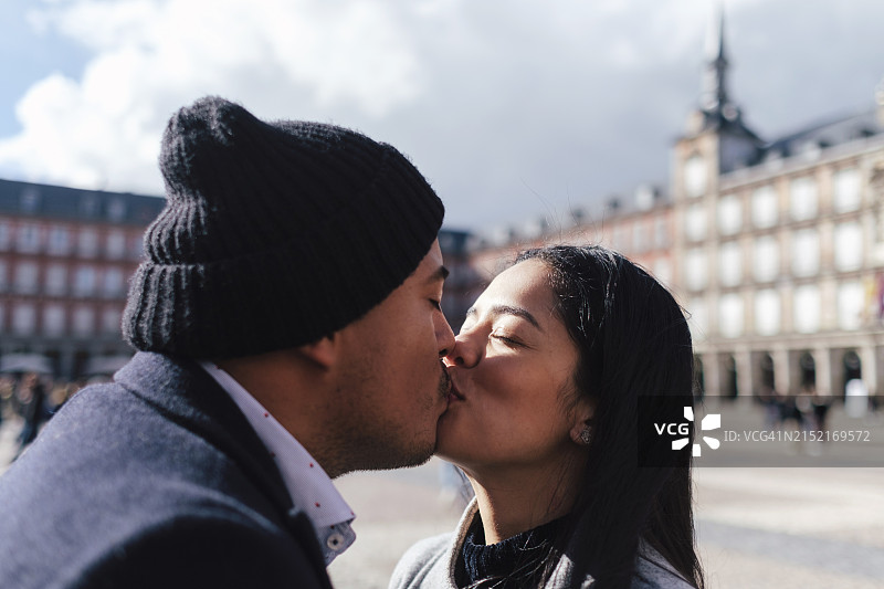 情侣在西班牙马德里面包房之家建筑前亲吻图片素材