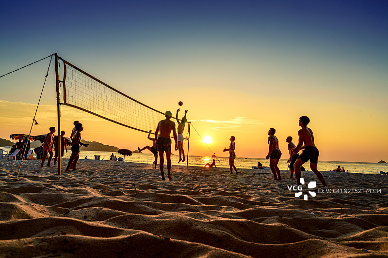 泰国普吉岛芭东海滩日落时游客打排球的仰视角度图片素材