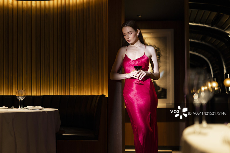 在高级俱乐部手持葡萄酒杯的美丽年轻女人图片素材