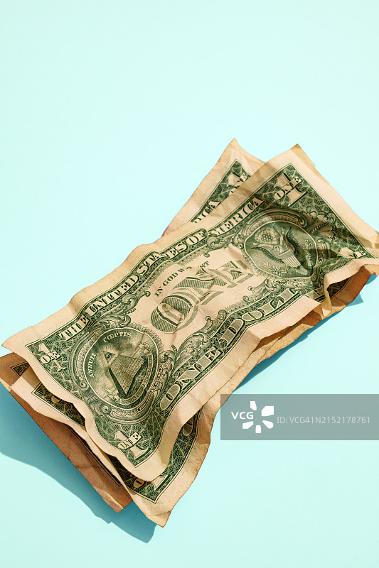 蓝色背景上的揉皱的一美元纸币图片素材