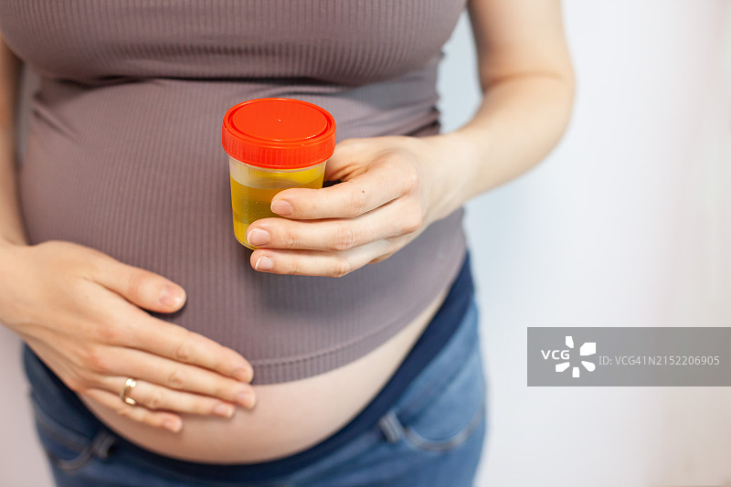 一位孕妇手拿一罐尿液样本图片素材
