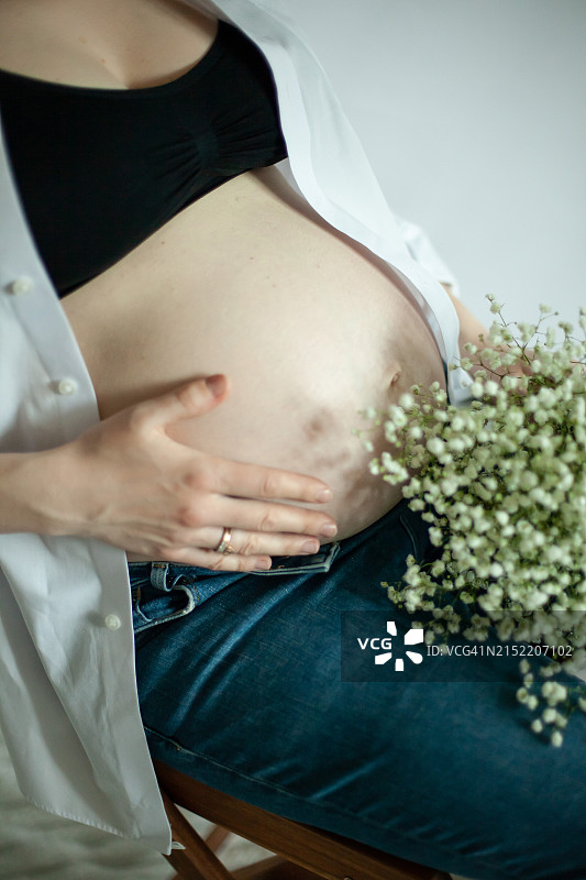 身穿白衬衫、手捧鲜花的孕妇（27-29周）图片素材