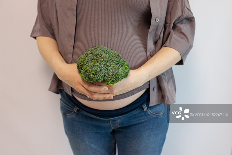 怀孕27-29周，手中拿着西兰花和扁豆图片素材