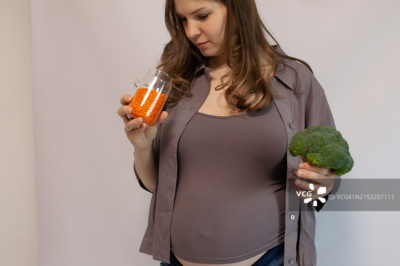 怀孕27-29周，手中拿着西兰花和扁豆图片素材