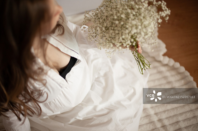 身穿白衬衫、手捧鲜花的孕妇（27-29周）图片素材