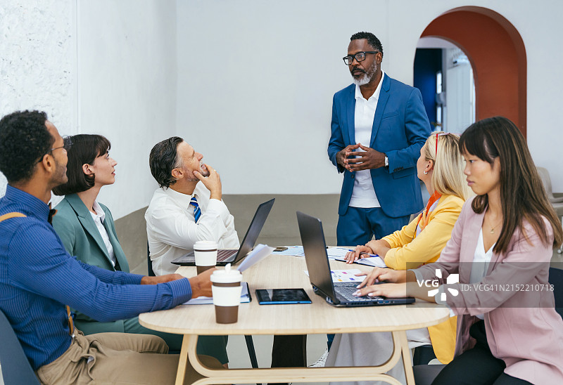 经理与同事在办公室办公桌旁规划策略图片素材