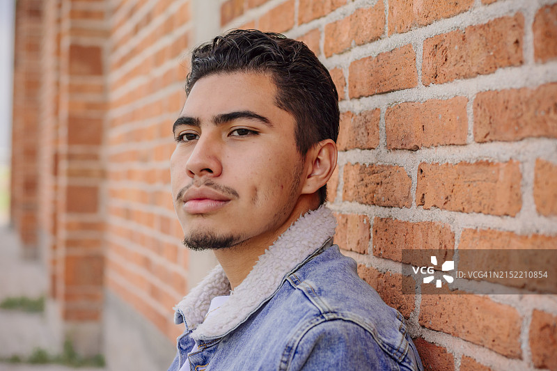 砖墙边的沉思的年轻人图片素材