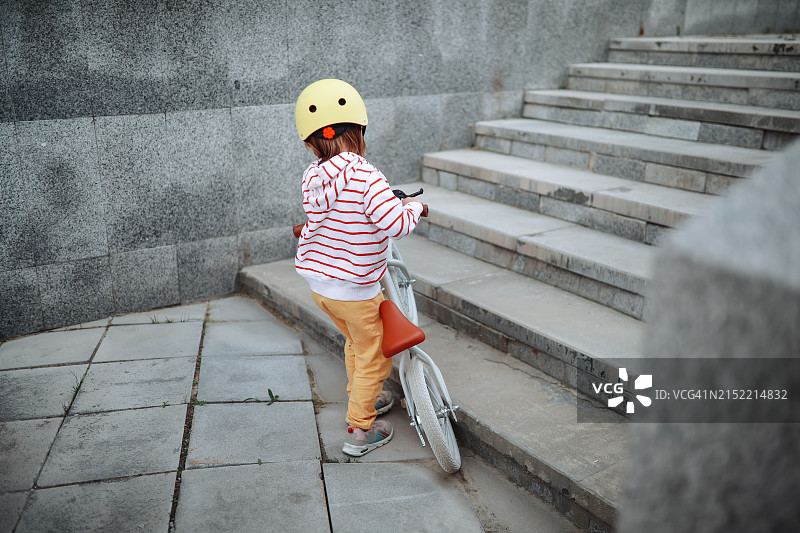 戴黄色头盔的年轻女孩在城市灰色路面上骑平衡车图片素材