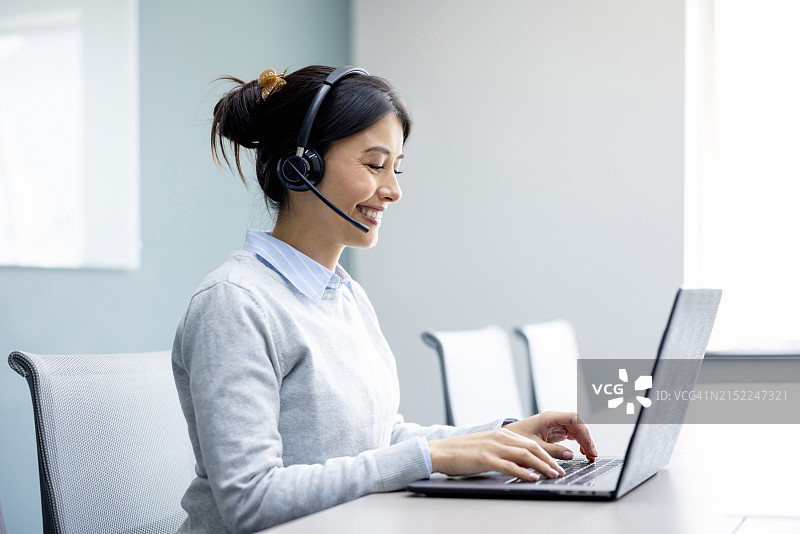 女商人在办公室工作，使用耳机进行视频通话图片素材