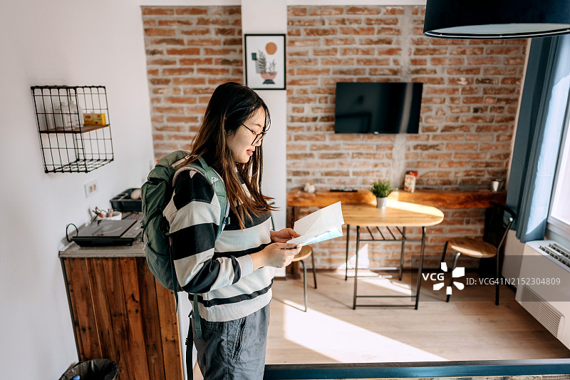 年轻女游客在进入酒店房间时阅读小册子的侧视图图片素材