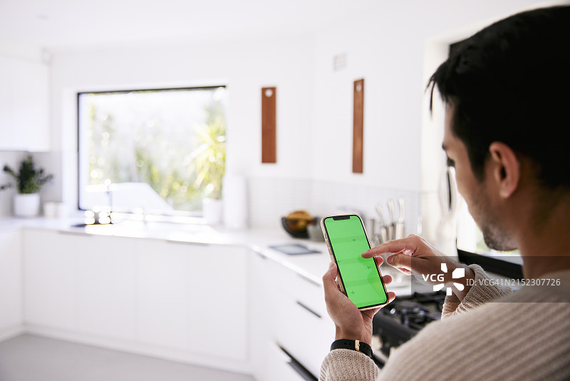 手持绿屏手机的男人背影图片素材