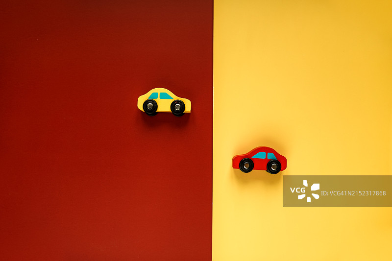 色彩对比：红色和黄色木制玩具车在红色和黄色背景上，象征选择图片素材